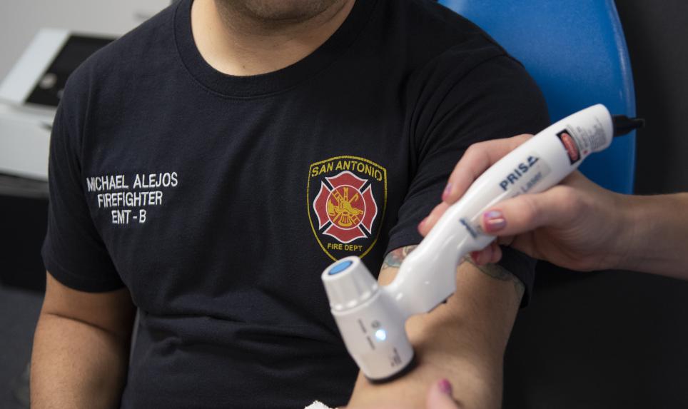 An athletic trainer assesses a firefighter's recovery of his forearm.